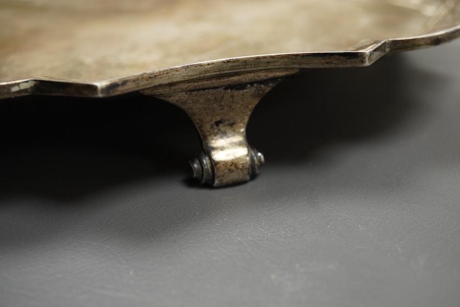 An early 20th century Indian white metal salver (tests as silver) by Hamilton & Co of Calcutta, of shaped square form, with inswept corners, on four scroll feet, 32.9cm, 38.7oz.